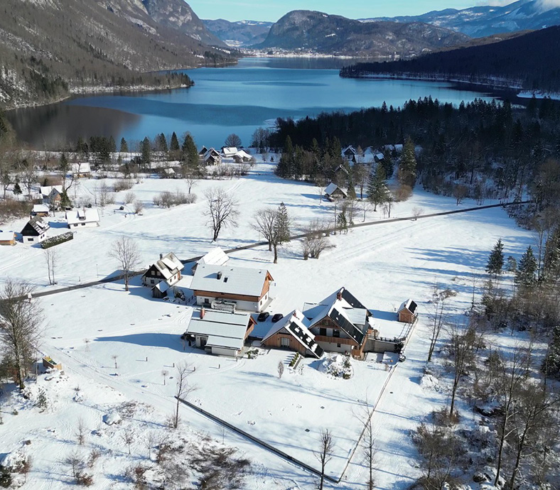 Winter drone view of Privillage Stare by Lake Bohinj, showing the boutique B&B, Villa and Chalet resort in Triglav National Park, Slovenia.