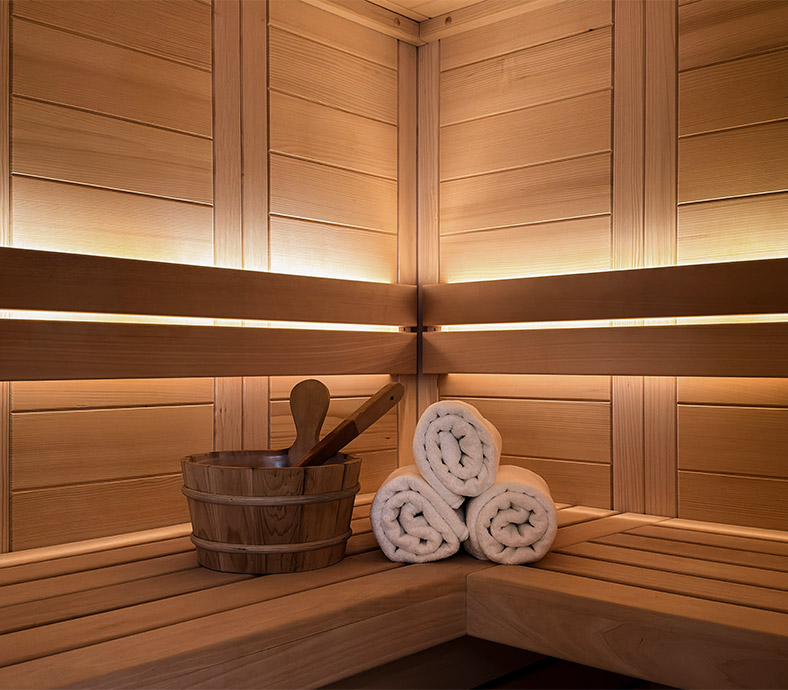 Private Finnish sauna in the Alpine SPA Chalet in Bohinj with wooden sauna bucket and rolled towels.